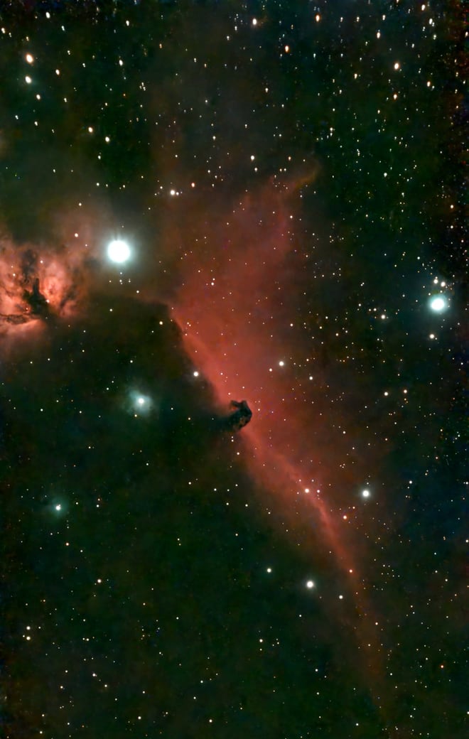 The dark Horsehead Nebula silhouetted against a red curtain of glowing hydrogen, with the orange Flame Nebula beside the bright star Alnitak.