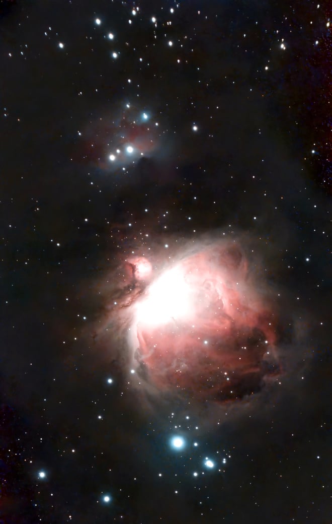 The Orion Nebula: a bright pink and white cloud of gas with dark dust lanes, the smaller Running Man Nebula above it, on a starfield.