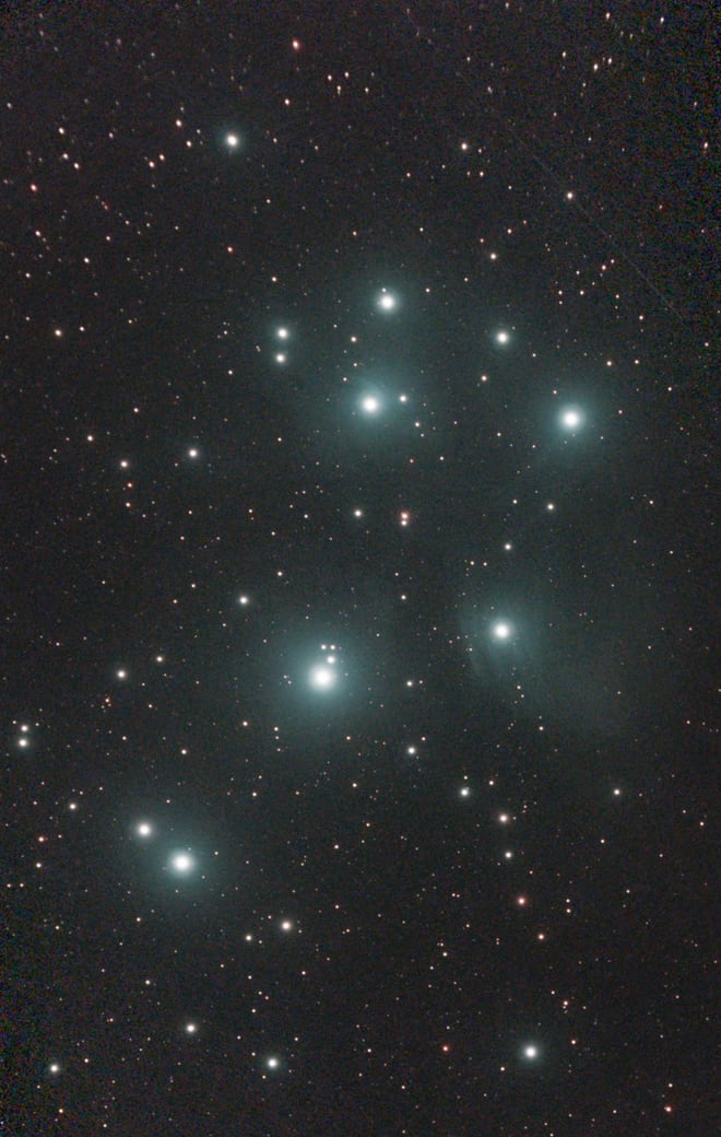 The Pleiades: a cluster of bright blue-white stars wrapped in faint blue reflection nebulosity.